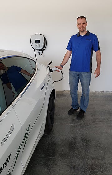 Adam Westaby, of Eau Claire Energy Cooperatives, plugs in a Tesla 3 to a Level 2 charger installed into a new home.